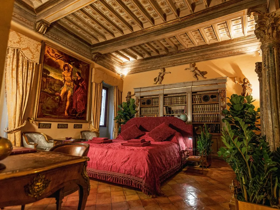 Main bedroom at Giordano Segreto with burgundy bed, library and historic ceiling